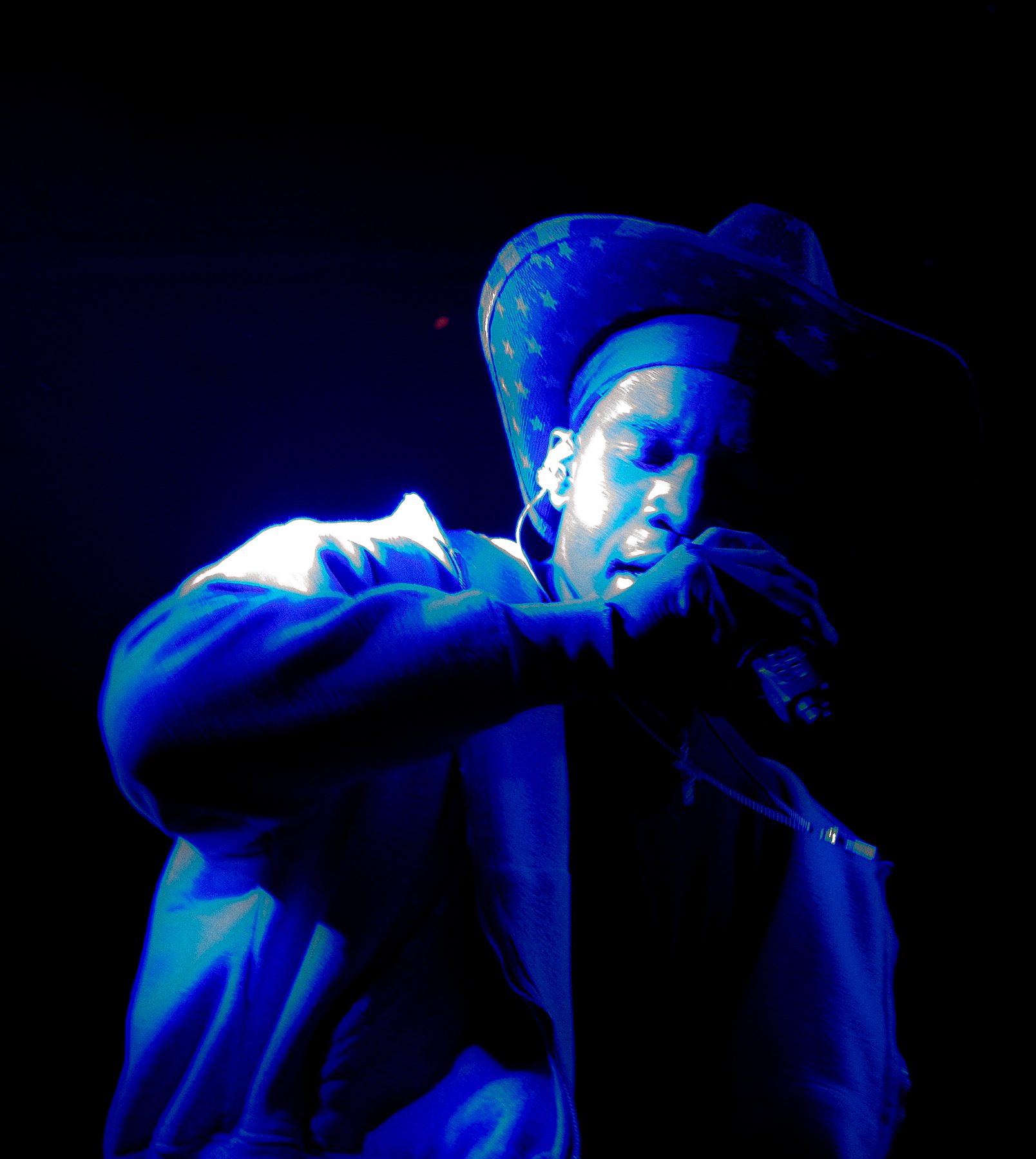Performer under blue stage lighting wearing a star-patterned cowboy hat